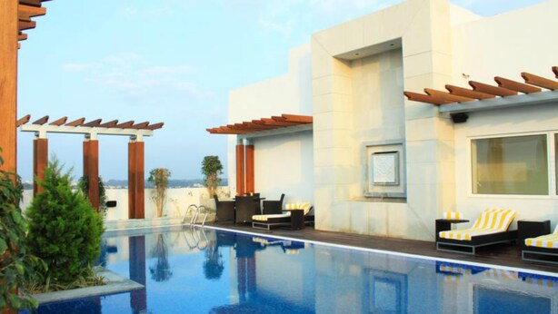 A pool area with a clear view of the pool, lounge chairs, and a pergola structure. - Lemon Tree Hotel Gachibowli Hyderabad (Hyderabad)