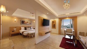 A hotel room with a bed, bedside table, lamp, TV, seating area, and a city view. - Lemon Tree Hotel Gachibowli Hyderabad (Hyderabad)