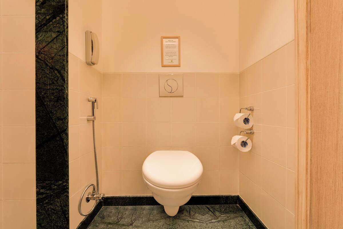 Ein Badezimmer mit Toilette, einem Händetrockner und einem Papierhandtuchspender.