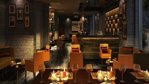 A dimly lit restaurant with brick walls, wooden tables, and orange chairs. - Lemon Tree Hotel Gachibowli Hyderabad (Hyderabad)