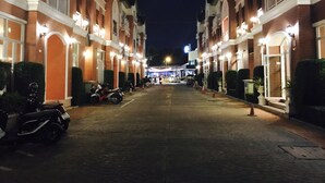 Une rue bordée d’immeubles à plusieurs étages, chacun doté de balcons et de fenêtres illuminées, ce qui laisse supposer qu’il s’agit d’un quartier hôtelier ou résidentiel.
