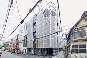 Un edificio moderno con fachada de entramado, una entrada visible y señalización que indica un establecimiento comercial.