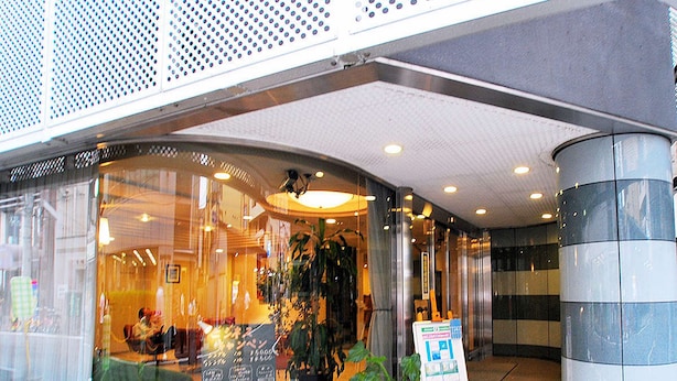 A hotel entrance with a reception desk, potted plants, and a signboard. - Hotel Le Botejour Nanba (Osaka)