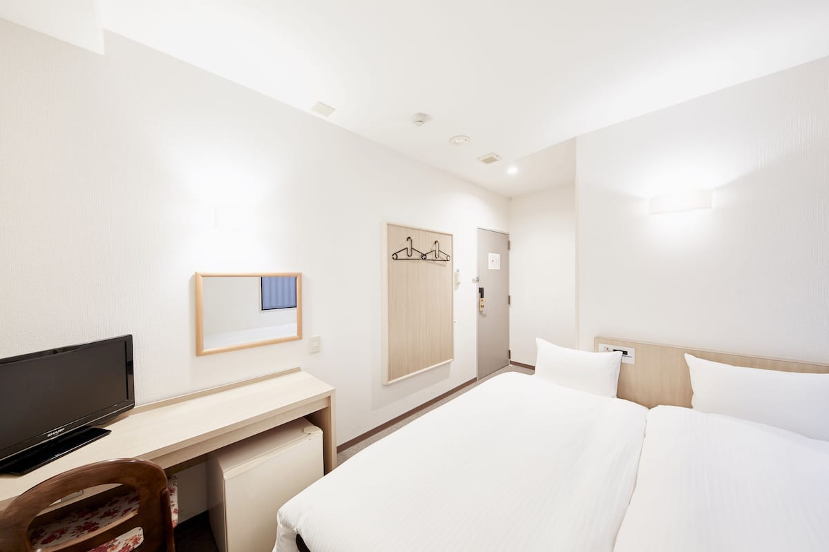 Une chambre d’hôtel équipée d’un lit, d’un bureau, d’une télévision et d’une armoire.