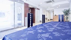 A hotel room with a large bed, a glass door leading outside, and a reception desk in the background. - Hotel Le Botejour Nanba (Osaka)