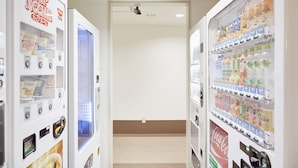 A hallway with vending machines on either side, including options for Cup Noodles and Coca-Cola. - Hotel Le Botejour Nanba (Osaka)