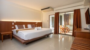 Una habitación de hotel moderna con una cama grande, cabecera de madera, mesita de noche, escritorio y vista al área exterior.