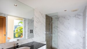 Un baño moderno con lavamanos de mármol, inodoro y ducha con mampara de vidrio.
