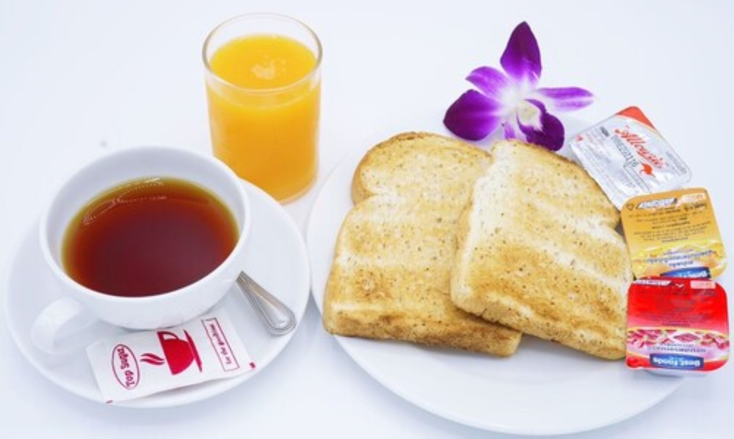 Desayuno con tostadas, zumo de naranja y una taza de té.