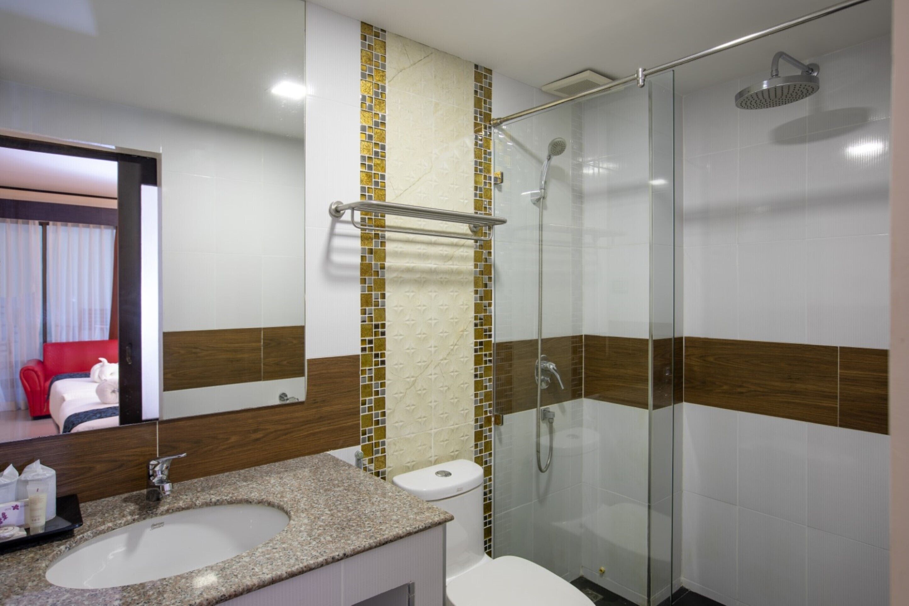 Une salle de bain moderne avec un lavabo sur un plan de travail en granit, une douche à parois de verre et des toilettes surmontées d’un porte-serviettes.