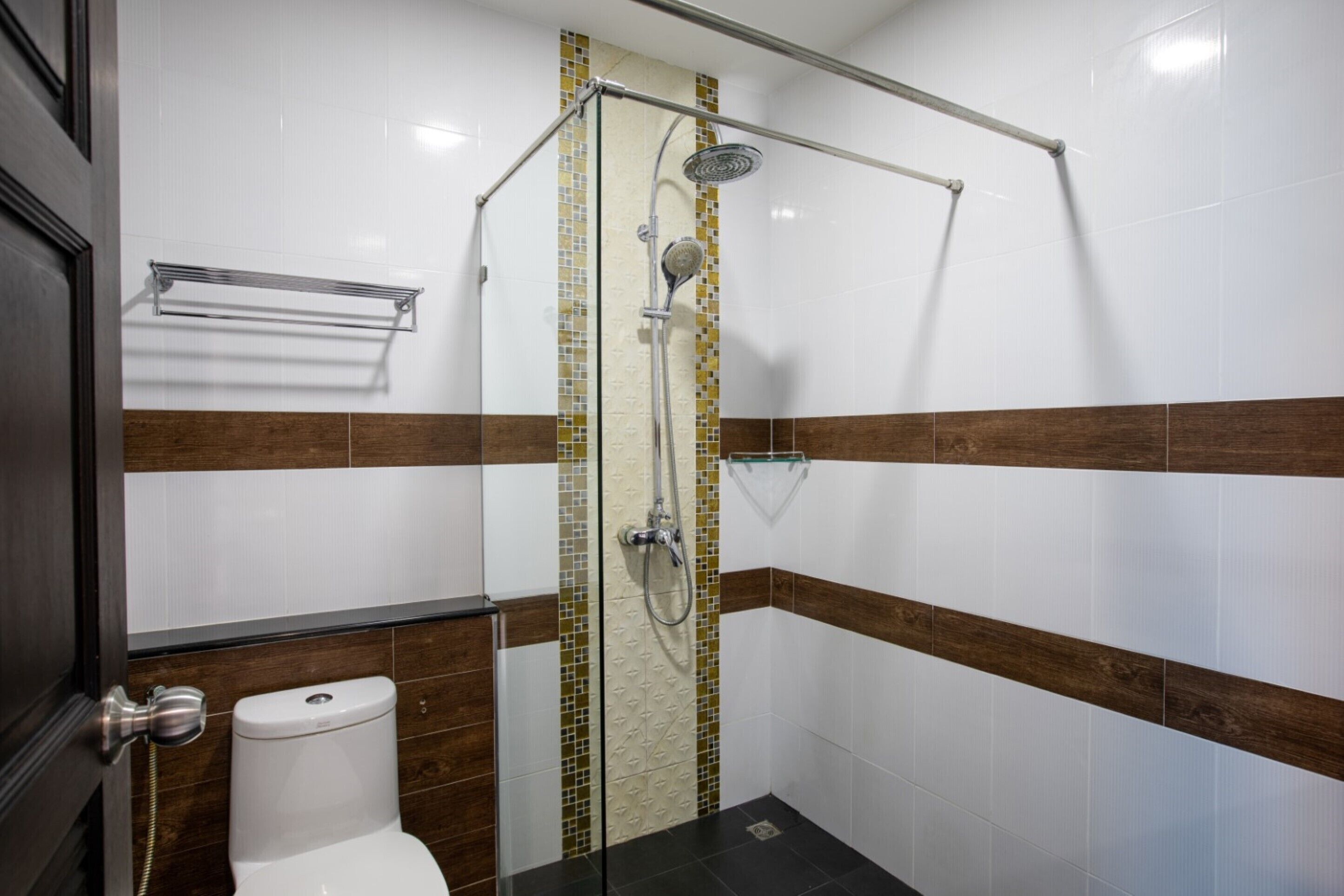 A bathroom with a shower, toilet, and a towel rack.