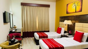 A hotel room with two beds, a TV, a desk, and a chair. - Fortune Hotel Deira (Dubai)