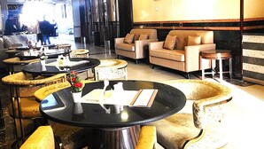A hotel lobby with round tables, sofas, and a large painting on the wall. - Fortune Hotel Deira (Dubai)