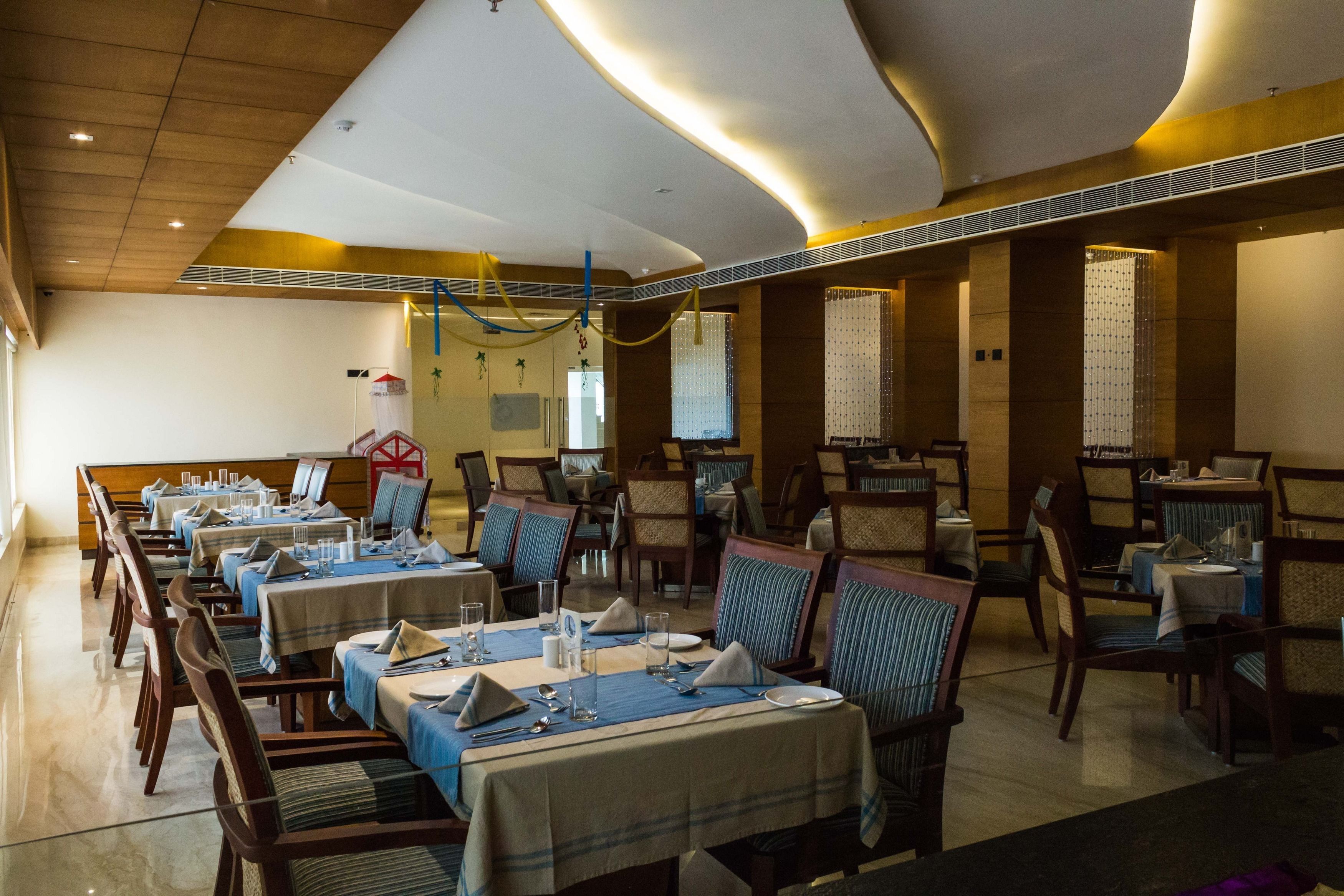 A restaurant with multiple tables set for dining, featuring a modern interior with wooden paneling and a high ceiling.