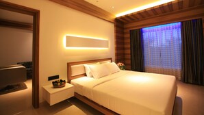Quarto de hotel moderno com uma cama grande, mesas de cabeceira, um espelho e uma janela com cortinas.