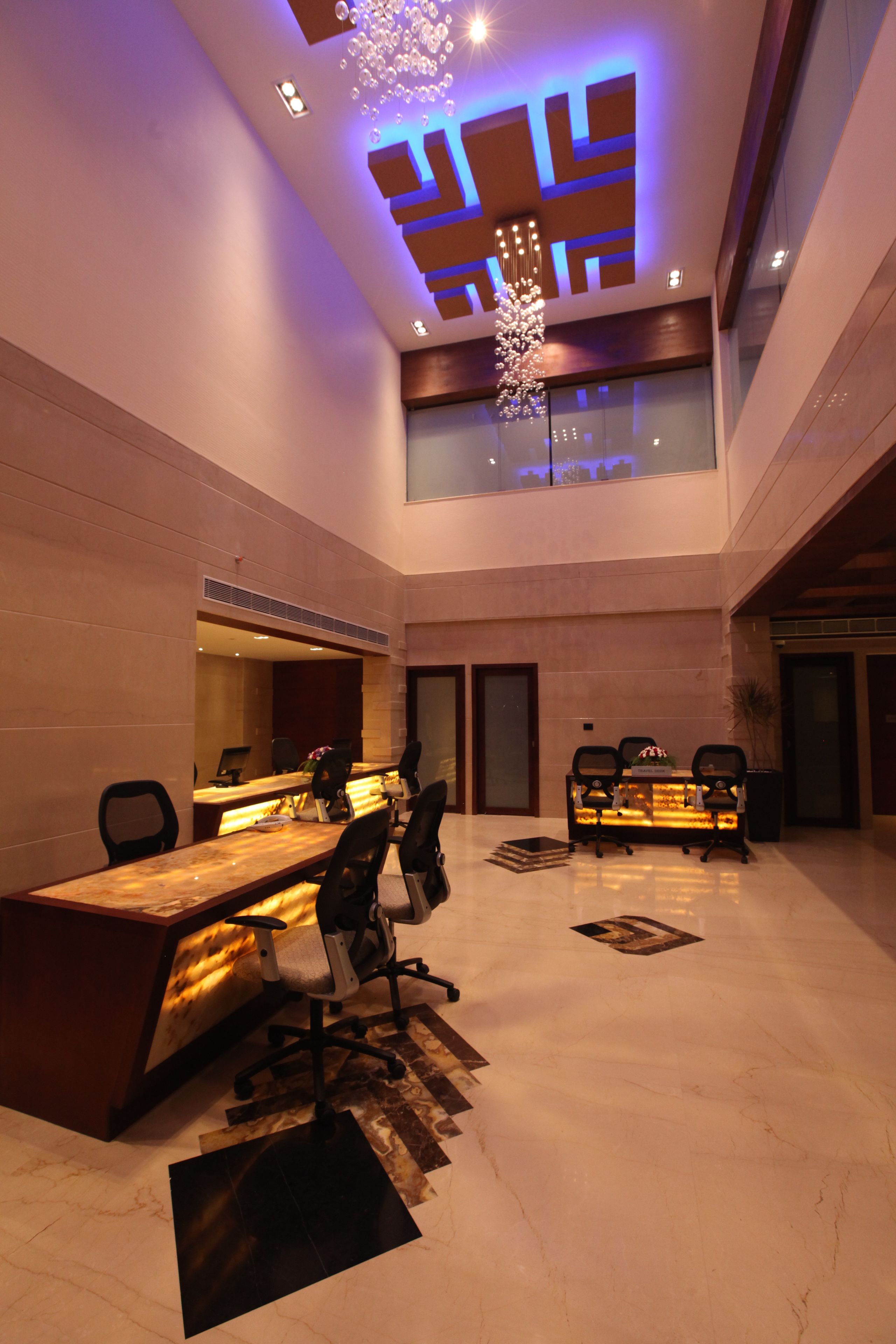 A modern reception area with a reception desk, seating, and a decorative ceiling light fixture.