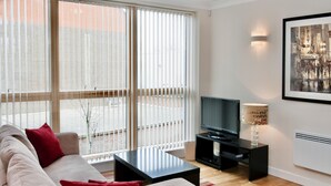Een moderne woonkamer met een bank, een salontafel, een televisie en een lamp.