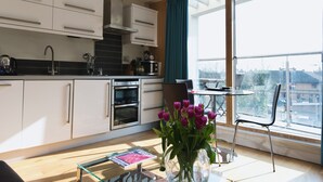 Een moderne keuken met witte kasten, een oven van roestvrij staal en een groot raam met uitzicht op de stad.