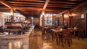 Restaurante con vigas de madera, zona de bufé y mesas de comedor.