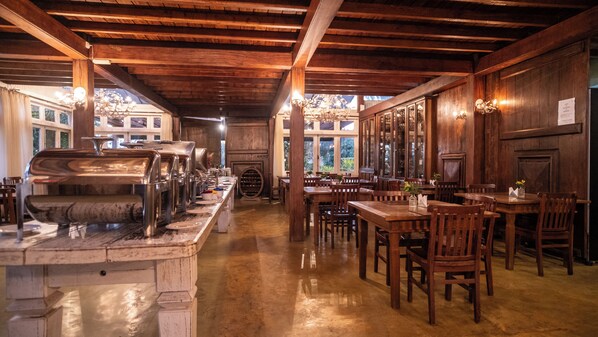 Restaurante con vigas de madera, zona de bufé y mesas de comedor.