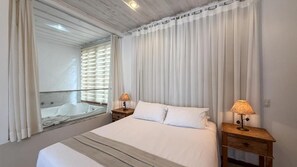 A hotel room with a large bed, two bedside tables with lamps, a window with curtains, and a view of a balcony. - Ville Real Hotel (Ouro Preto)