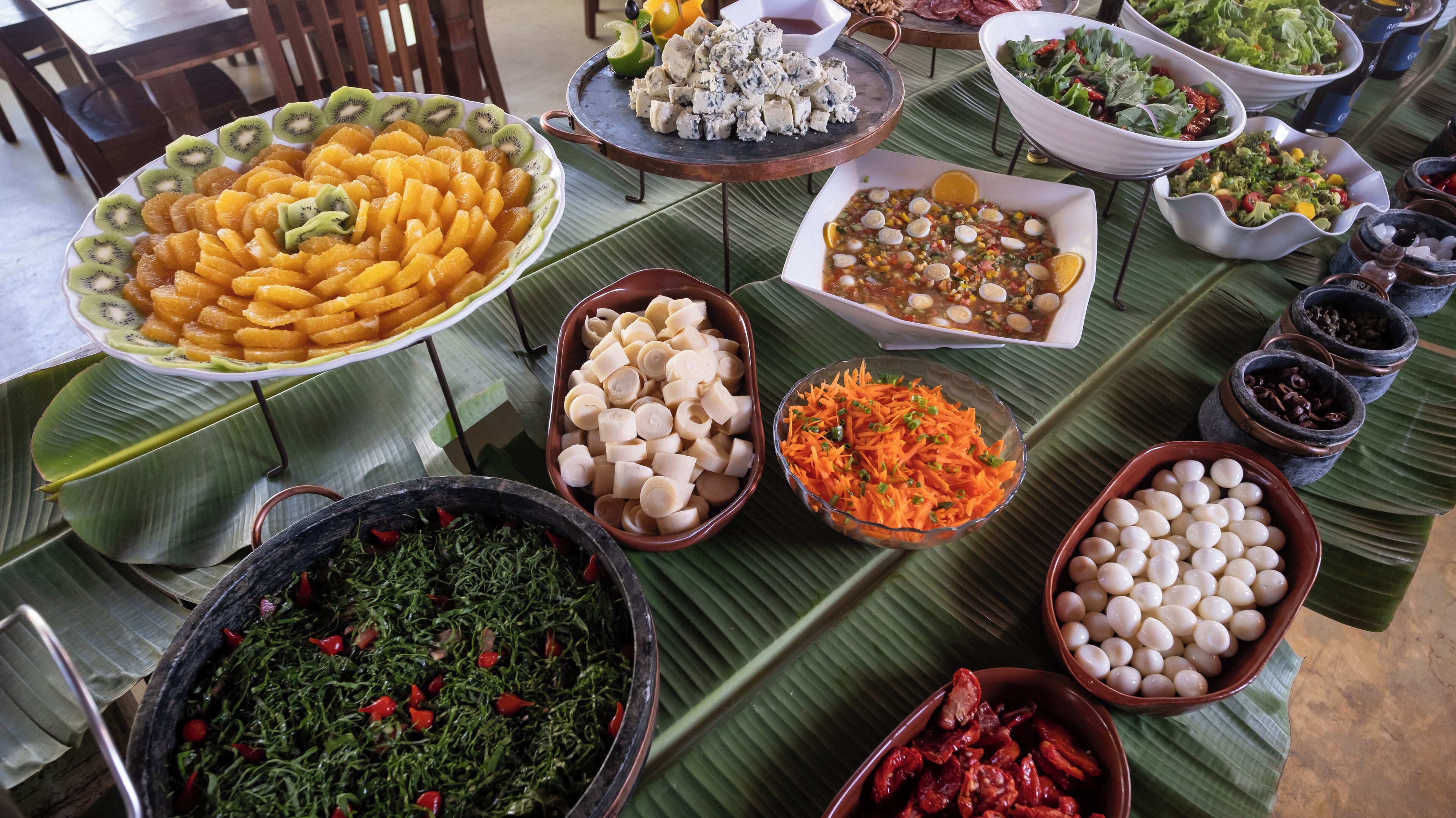 Una mesa con diversos alimentos, entre ellos frutas, verduras y otros platos.