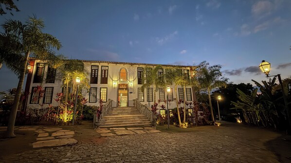 A two-story building with a stone staircase leading to the entrance, surrounded by tropical plants and a cobblestone pathway. - Ville Real Hotel (Ouro Preto)