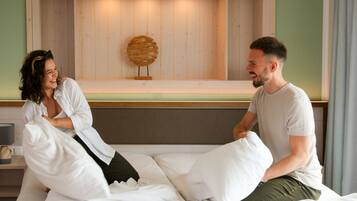 Una cama con ropa blanca, cabecera de madera y un adorno en la pared.