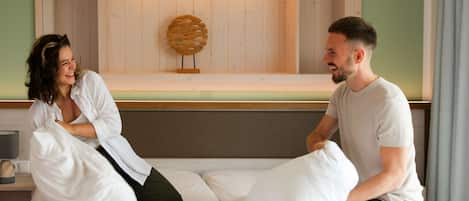 A bed with white bedding, a wooden headboard, and a wall-mounted decorative piece.