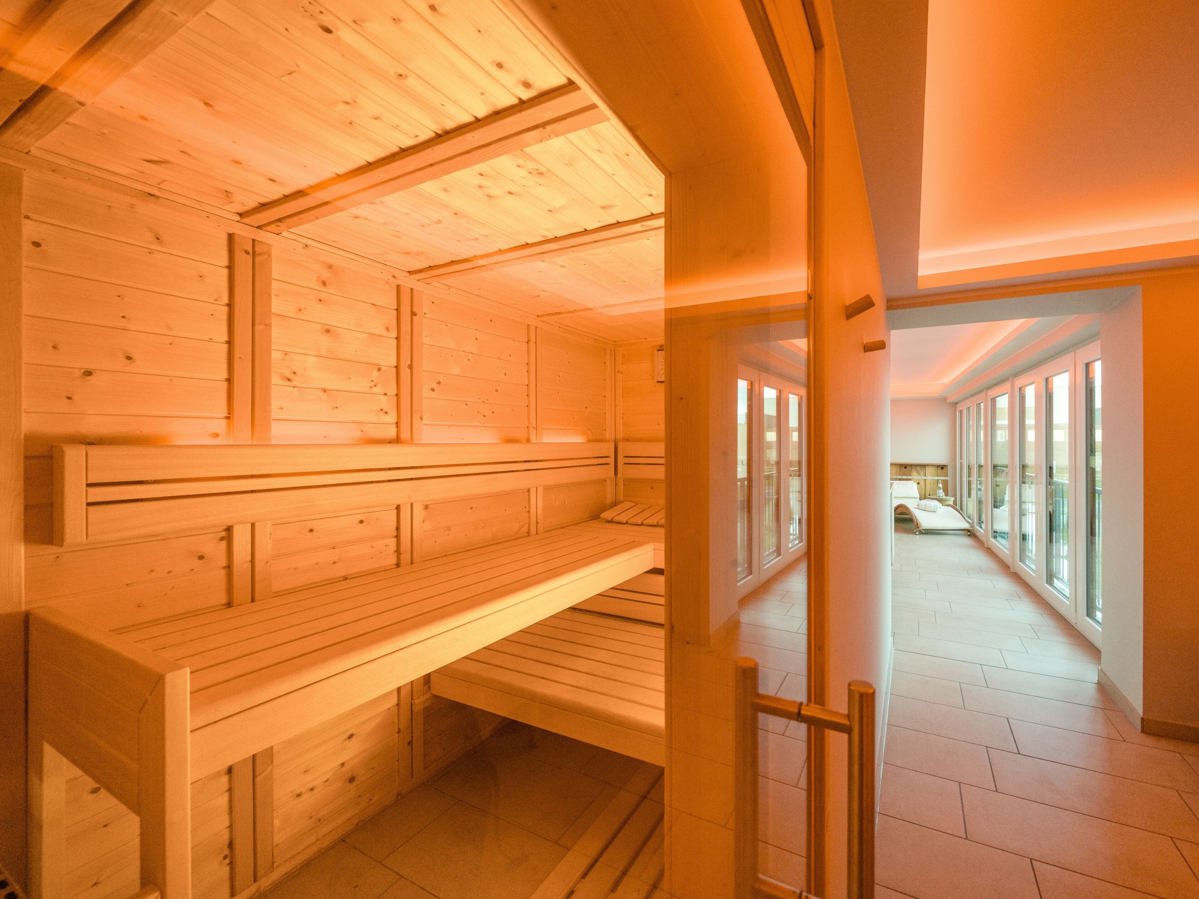 Una sala de sauna con bancos de madera y ventanas amplias.