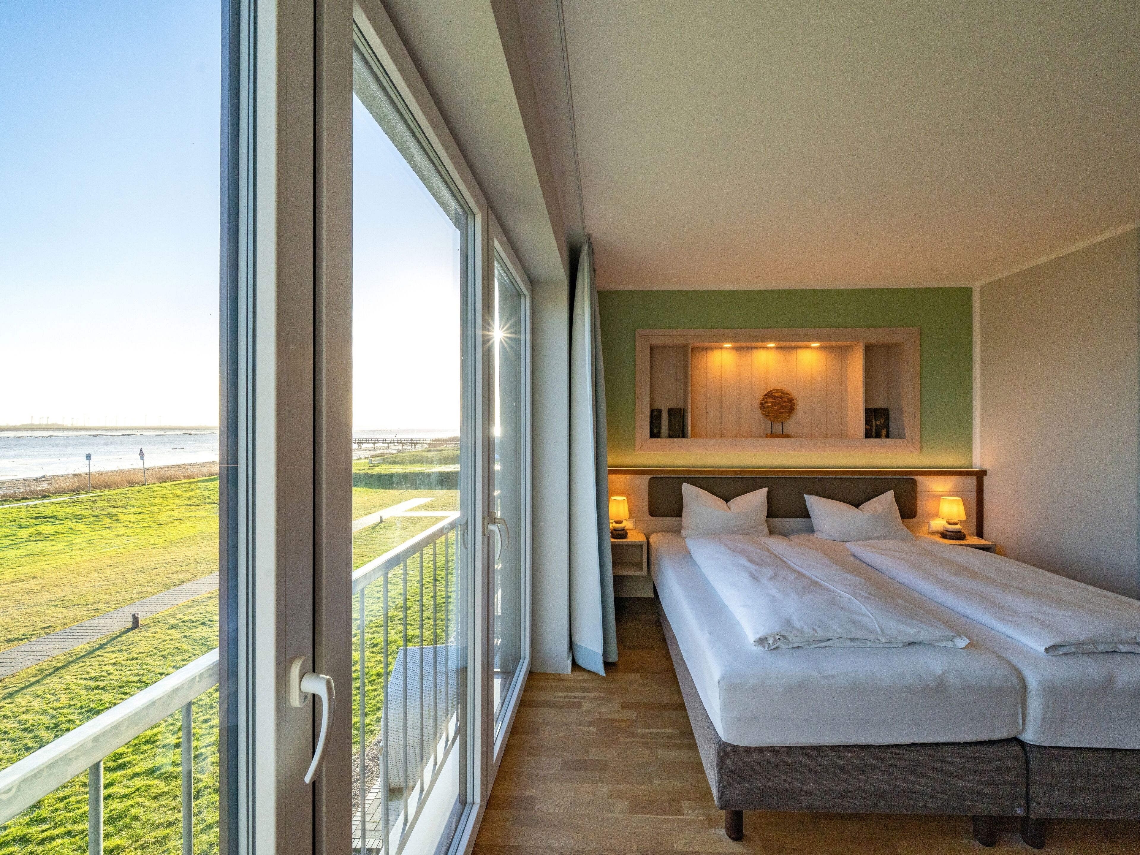 Une chambre avec une grande fenêtre, un lit, une table de chevet et une vue sur la plage.