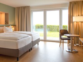 A hotel room with a bed, a chair, a table, and a large window.