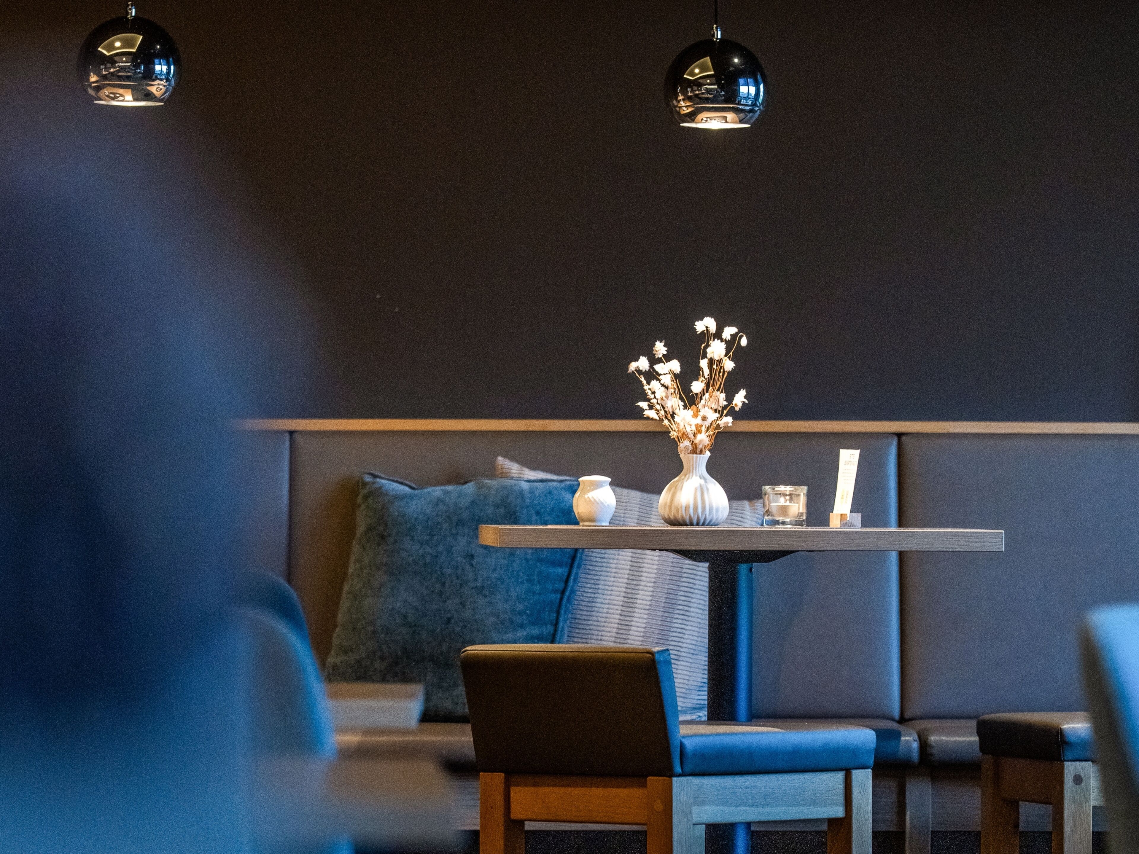 A modern interior with a round table, blue seating, and pendant lighting.