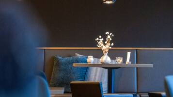 A modern interior with a round table, blue seating, and pendant lighting.