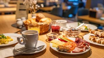 A breakfast setting with plates of food, a cup of coffee, and a basket of bread.