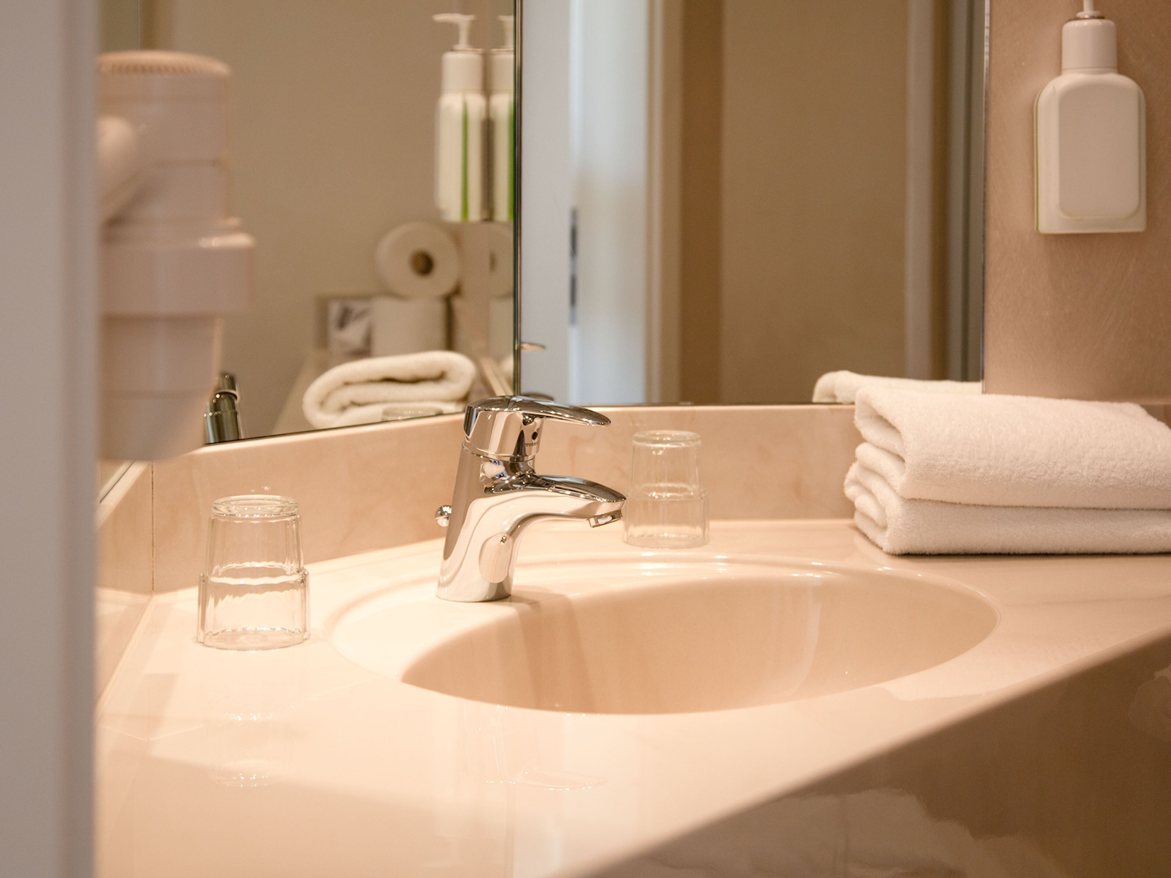 A bathroom sink with a mirror, a towel rack, and toiletries.