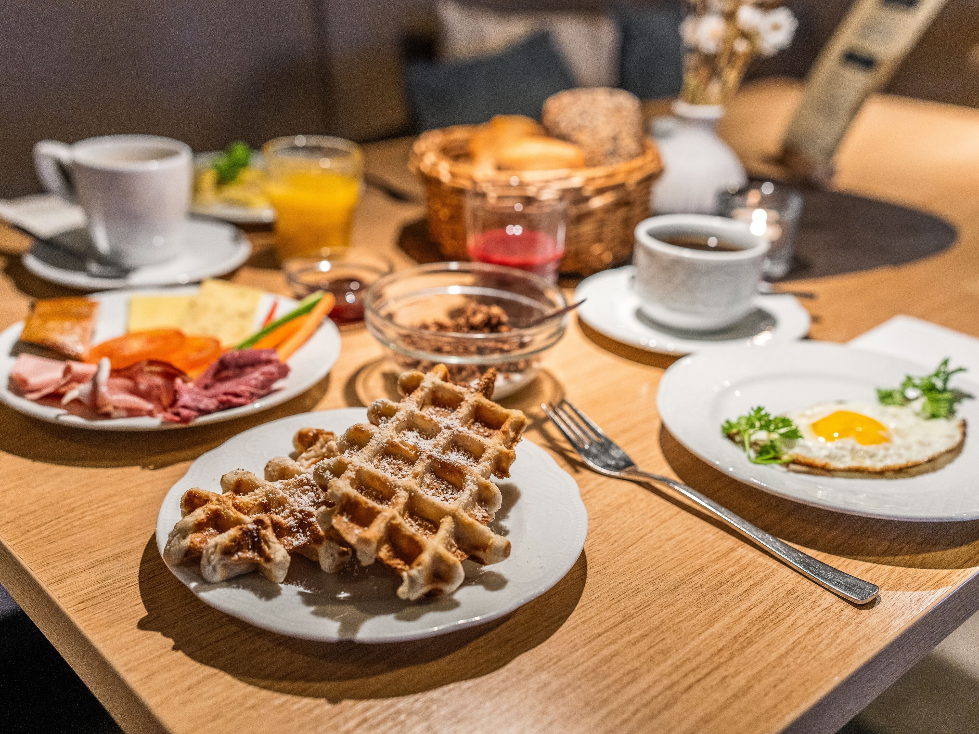 A breakfast setting with waffles, eggs, and various spreads on plates.