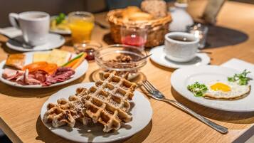 A breakfast setting with waffles, eggs, and various spreads on plates.