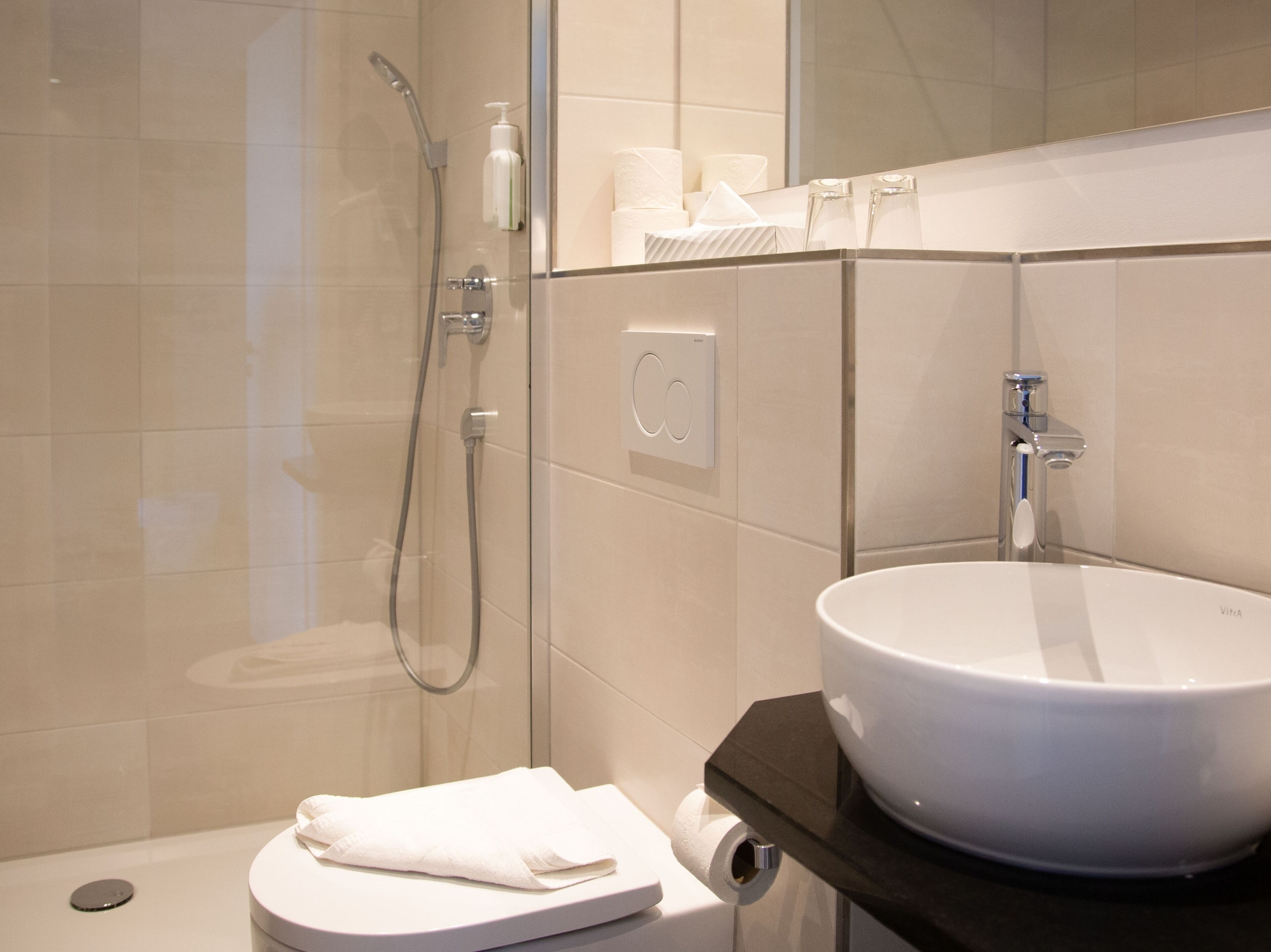 A modern bathroom with a glass shower enclosure, a white sink, and a toilet.