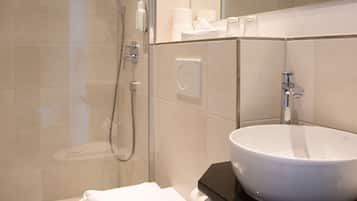 Un baño moderno con cabina de ducha de vidrio, lavamanos blanco y un inodoro.