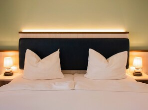 A hotel room with a bed, two bedside lamps, and a headboard. - BE BIO Hotel be natural (Toenning)