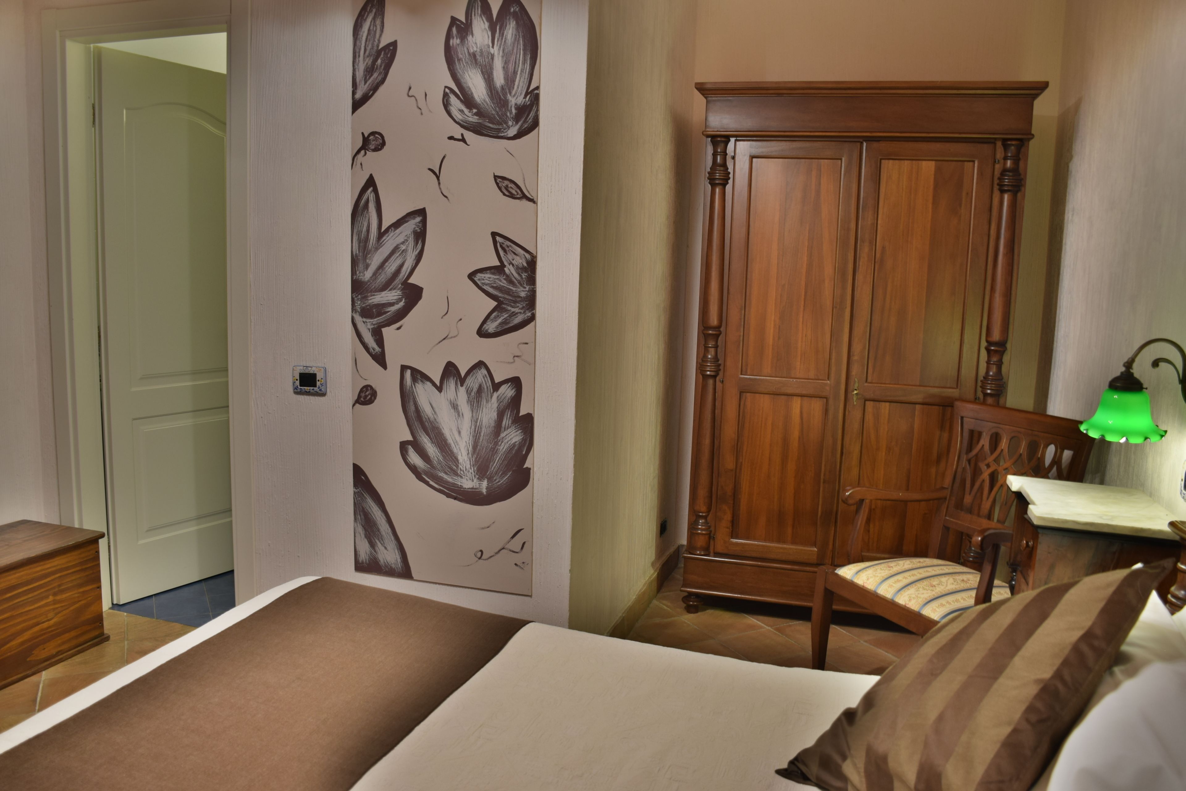 Um quarto com cama, guarda-roupa de madeira, cadeira e mesa de cabeceira.