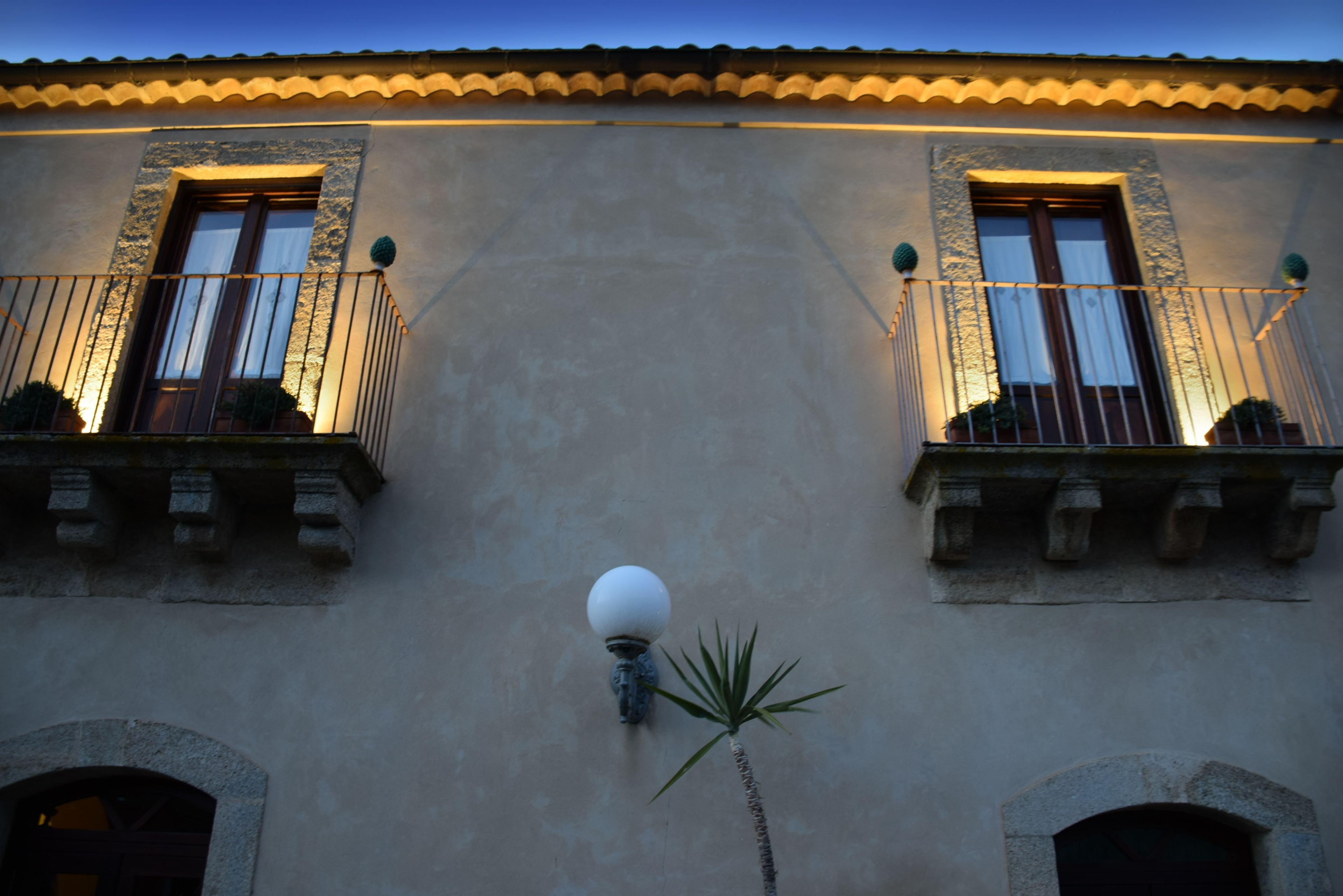 A building with two balconies, each with a railing and potted plants.
