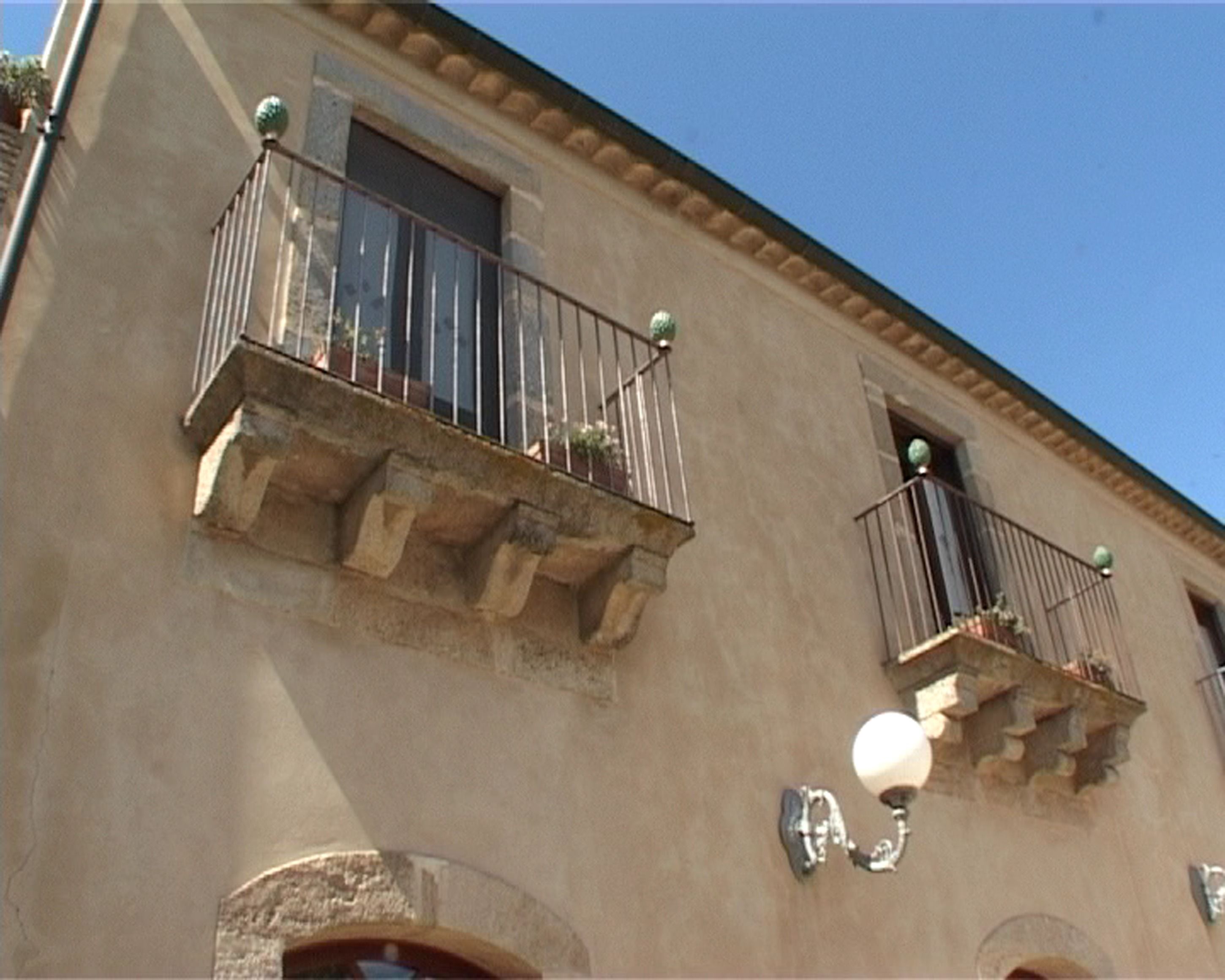 A building with two balconies, each with a small railing and a spherical light fixture.