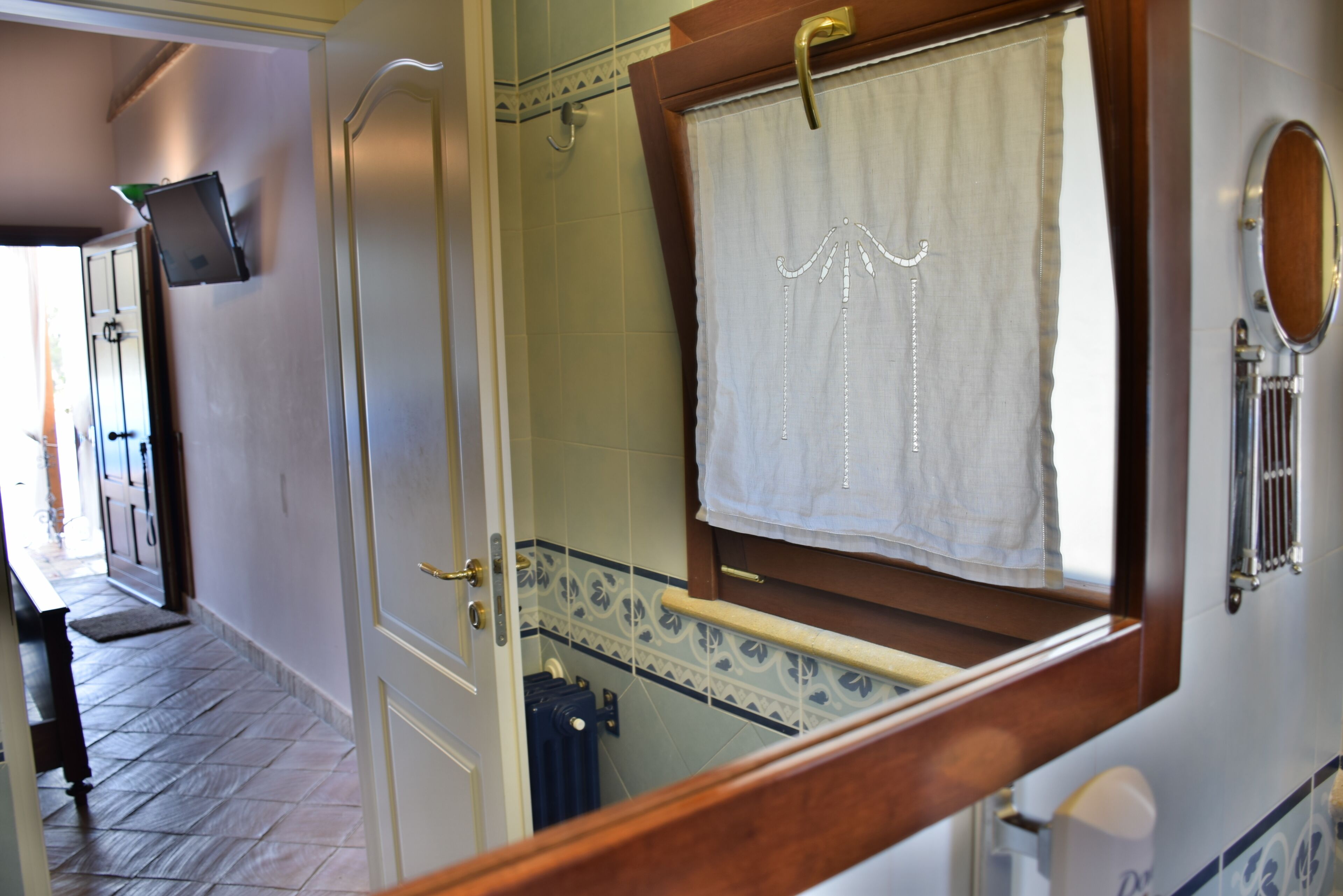 A bathroom with a wooden door, a towel hanging on a rack, and a mirror on the wall.