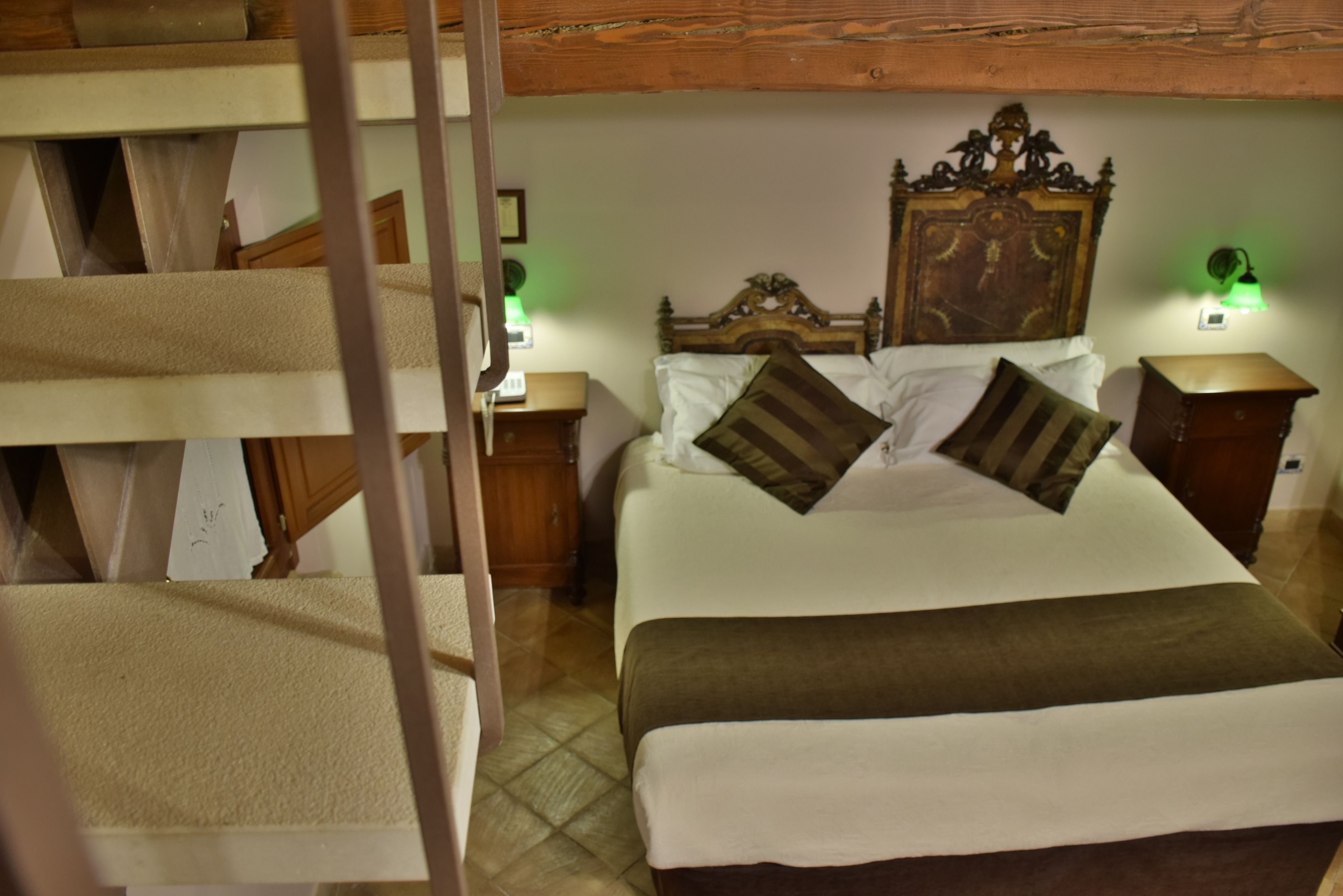 A bunk bed room with a wooden headboard, a bedside table, and a nightstand with a lamp.