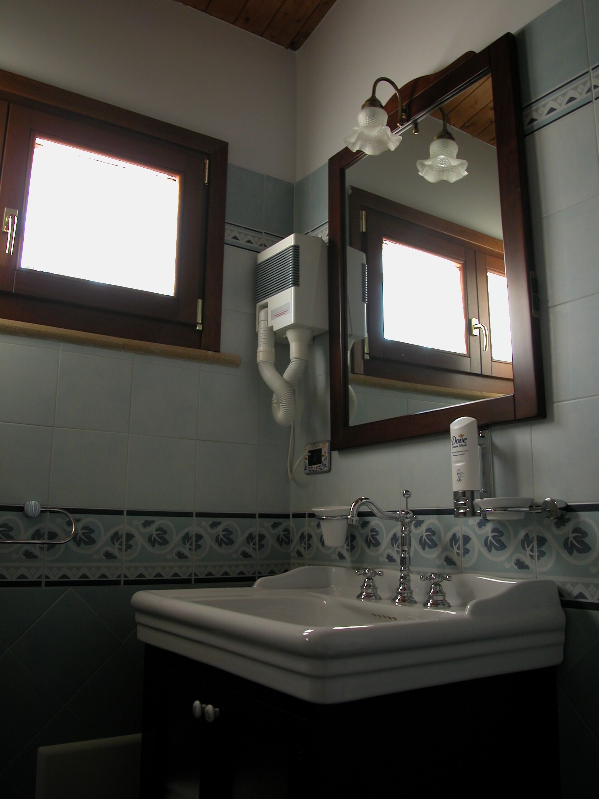 Un baño con lavamanos, espejo y ventana.