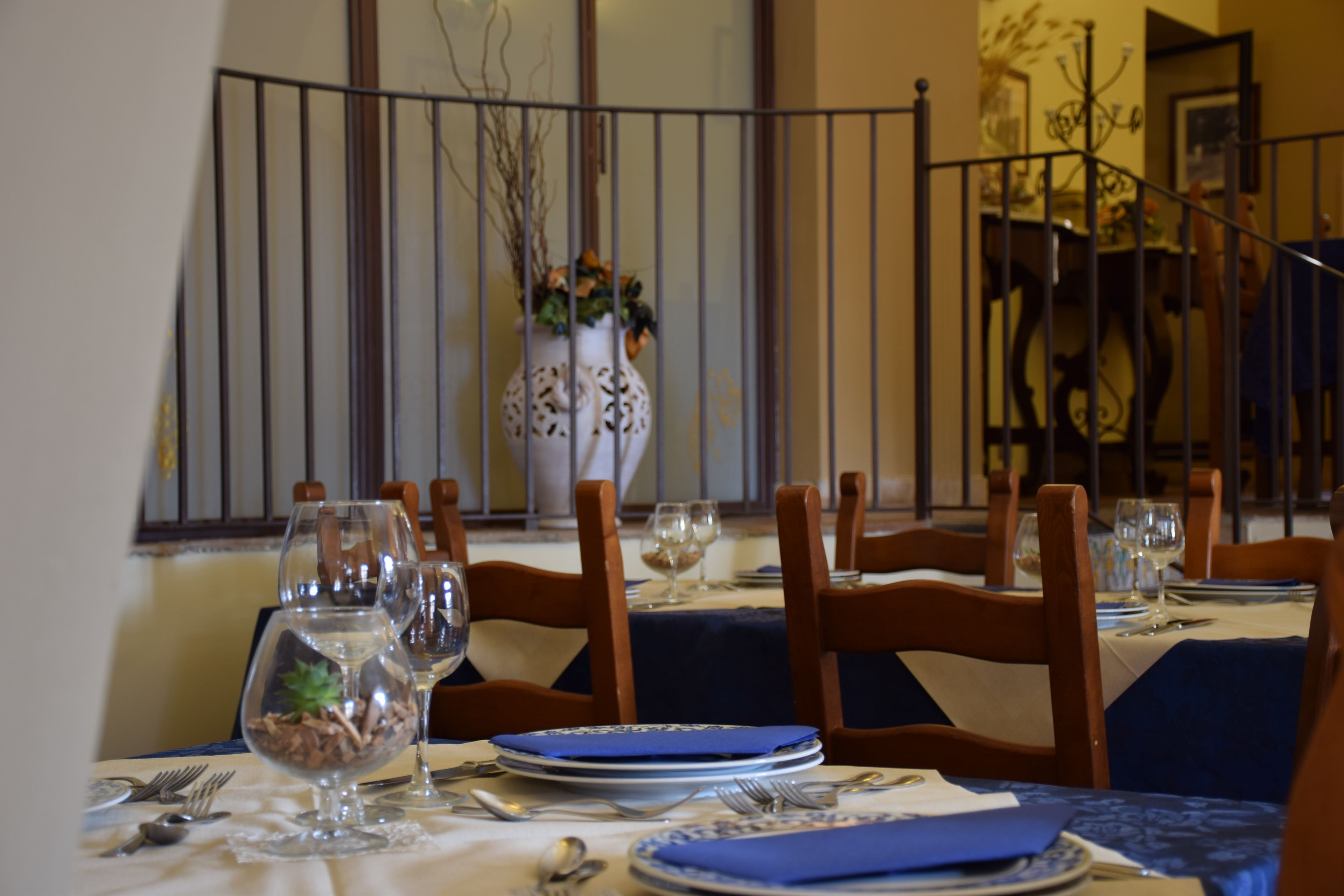 A dining table set with blue tablecloths, white plates, and silverware.