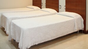 Habitación de hotel con dos camas, cabeceros de madera, televisión de pantalla plana e iluminación empotrada en el techo.