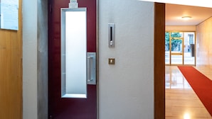 A modern hotel entrance with a red door, a glass panel, and a red carpet leading to a well-lit interior. - Guest House Train Station (Mestre)